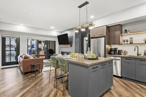 A modern kitchen with grey cabinets, a central island, and a dining area with a sofa and chairs.