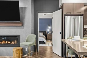 Una habitación de hotel moderna con chimenea, comedor y cocina.