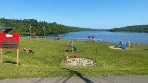 Un parque con juegos infantiles, bancos y vistas a un lago.