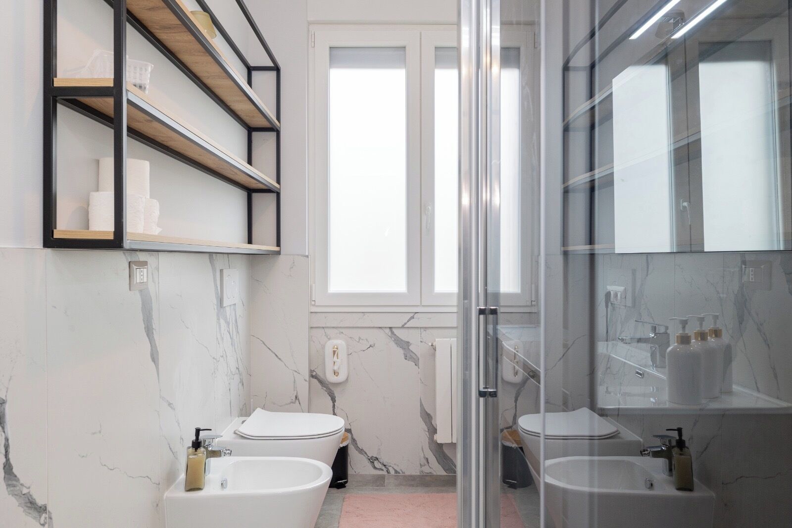 Ein modernes Badezimmer mit zwei Toiletten, einem Bidet und einer separaten Duschkabine.