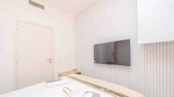 A hotel room with a bed, a TV mounted on the wall, and a door.