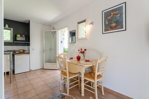 A dining area with a table, chairs, and a vase of flowers. - Charming Mazet in Secure Residence with Pool Near Alpilles and Town Center (Saint-Rémy-de-Provence)