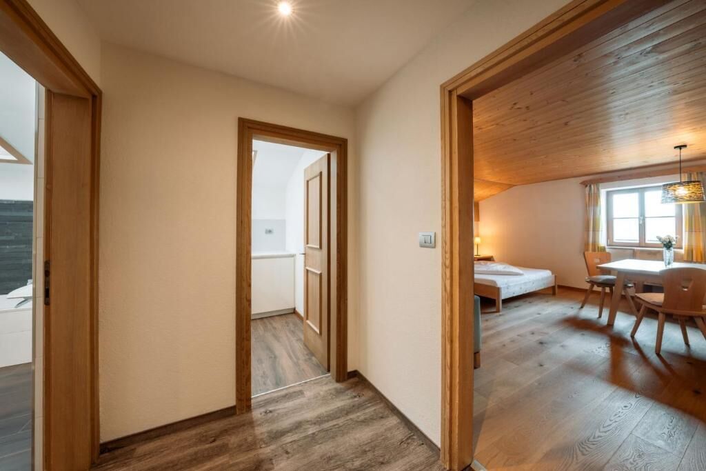 Quarto com piso de madeira, uma cama, uma escrivaninha e uma janela.