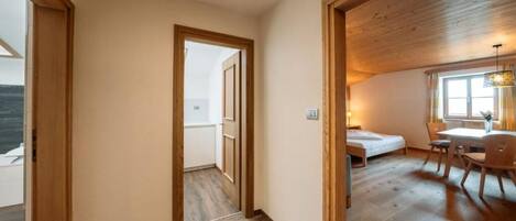 Quarto com piso de madeira, uma cama, uma escrivaninha e uma janela.