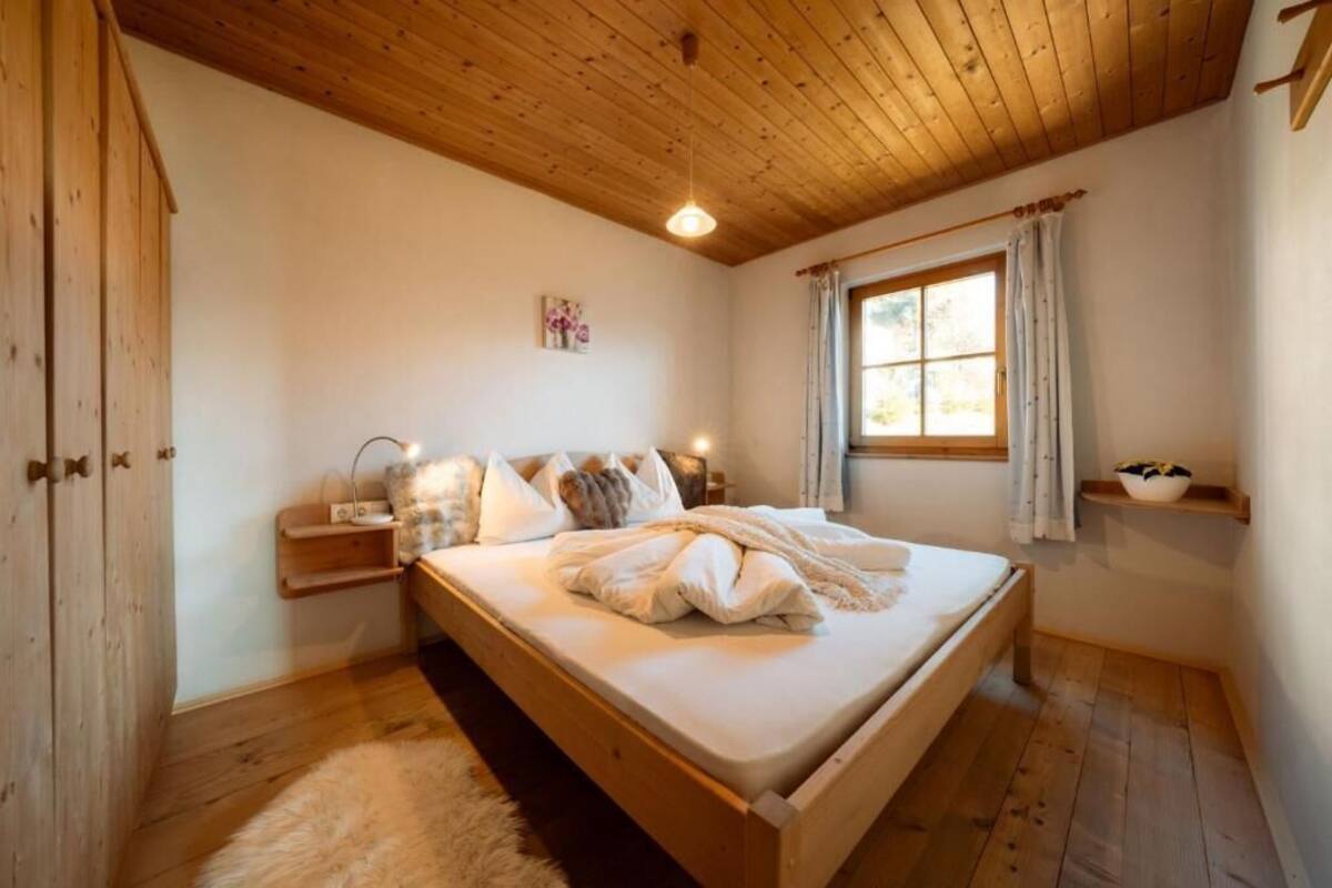 Une chambre à coucher avec un cadre en bois, comprenant un lit, une table de chevet et une fenêtre avec des rideaux.