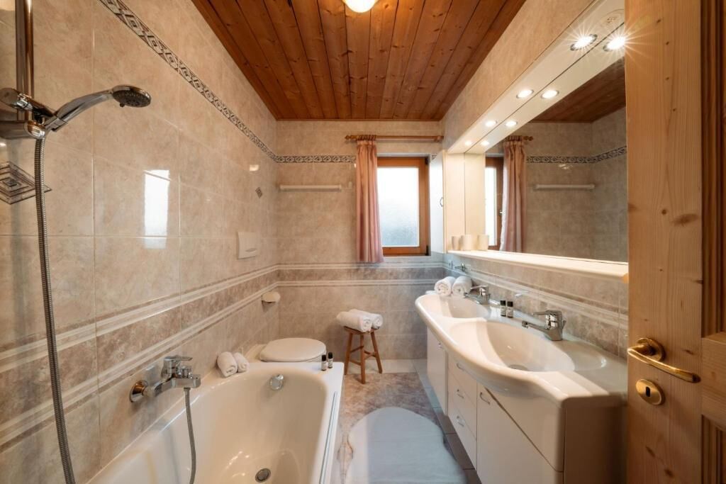 A bathroom with a wooden ceiling, a shower, a bathtub, two sinks, and a mirror.