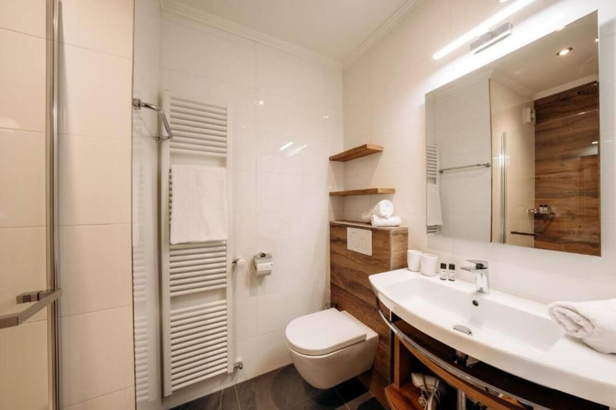 Une salle de bain moderne équipée d’une douche, de toilettes, d’un meuble-lavabo et d’un grand miroir.