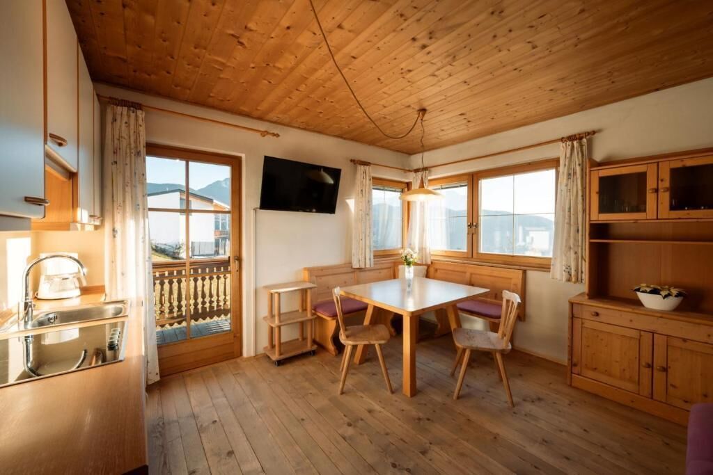 Ein Holzinterieur mit Esstisch, Stühlen, Küchenzeile und großen Fenstern mit Blick.