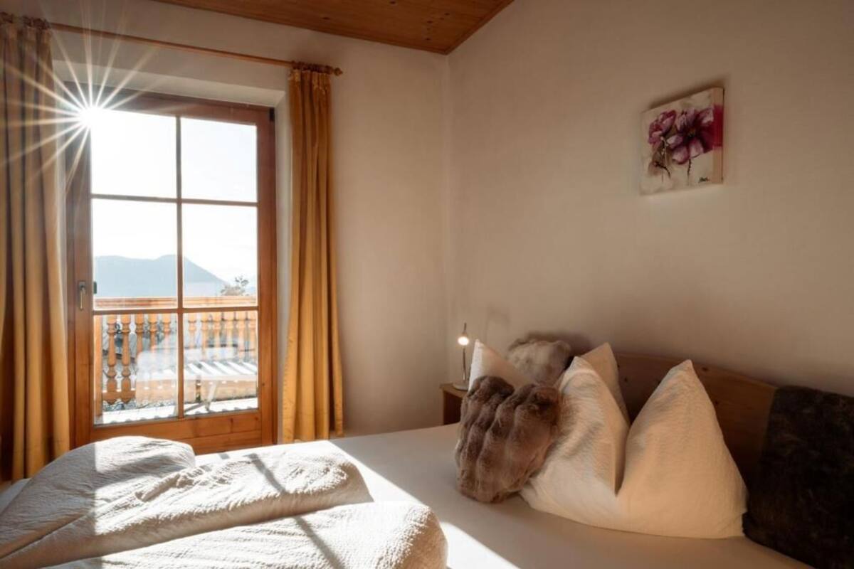Une chambre à coucher avec un lit, des oreillers, une table de chevet, une fenêtre avec des rideaux et un tableau au mur.