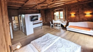 A wooden cabin interior with a bed, a TV, a dining table, and a sofa. - Garni Tschutscherhof (Laion)