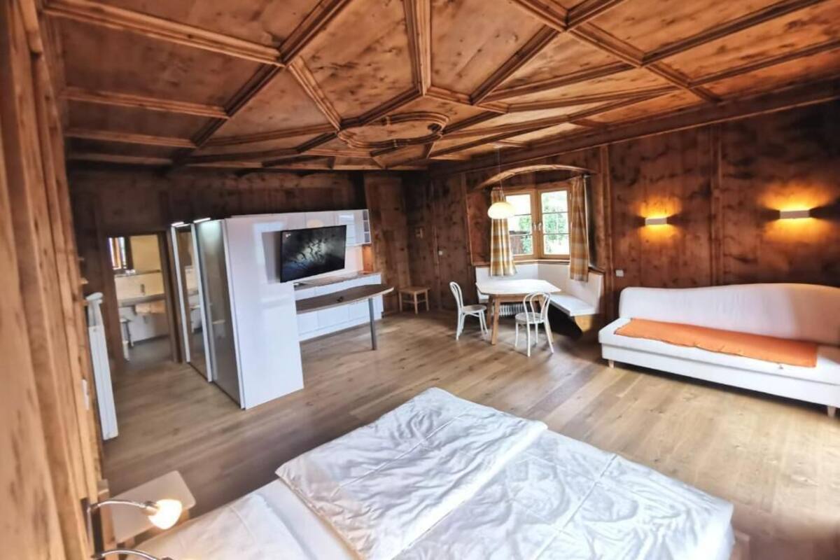 L’intérieur d’un chalet en bois comprend un lit, un téléviseur, une table à manger et un canapé.