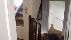 Un escalier avec des rampes en bois menant à une porte dont les panneaux sont en verre dépoli.
