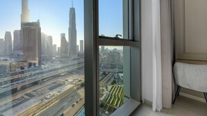 Een hoog gelegen kamer met een groot raam met uitzicht op een stadsbeeld, inclusief hoge gebouwen en een snelweg.
