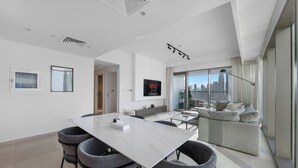 Een moderne woonkamer met een eethoek, een grote televisie en uitzicht over de stad.