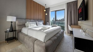 Een moderne hotelkamer met een groot bed, een bureau, een televisie en uitzicht op de stad.