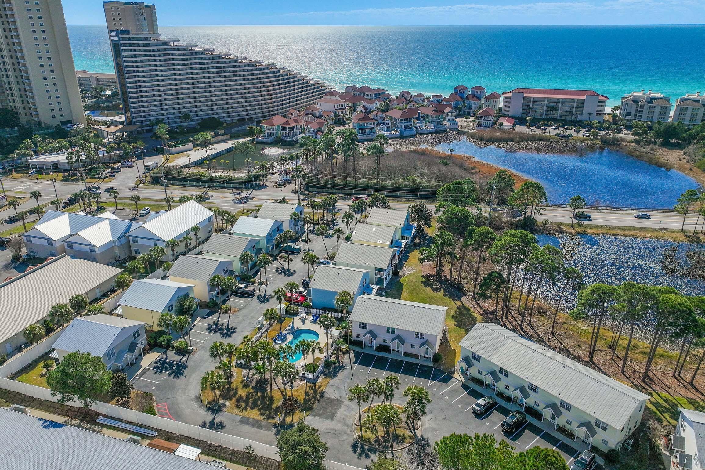 An aerial view of a coastal hotel area with multiple buildings, a swimming pool, and a beach.