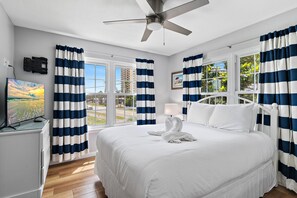Ein Hotelzimmer mit Bett, Deckenventilator, Fernseher und einem Fenster mit Vorhängen.