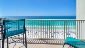 Un balcone con vista sulla spiaggia, una sedia e un tavolo.
