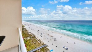 Vista sulla spiaggia dal balcone, cielo sereno, spiaggia sabbiosa e oceano.