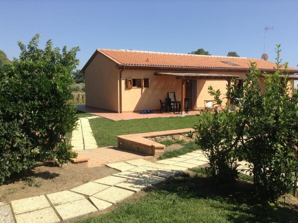 A single-story house with a tiled roof, a paved driveway, and a small patio area with outdoor furniture. - AGRITURISMO ISOLOTTO (Piombino)