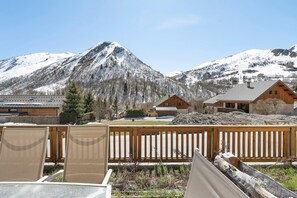 Une vue sur la montagne avec des chalets en bois, une clôture en bois et une chaise au premier plan.
