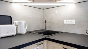 Una kitchenette compacta con tostadora, hervidor y pileta.