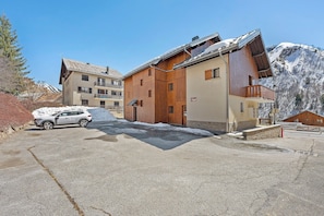 A building with a wooden facade, a car parked in front, and snow on the ground.