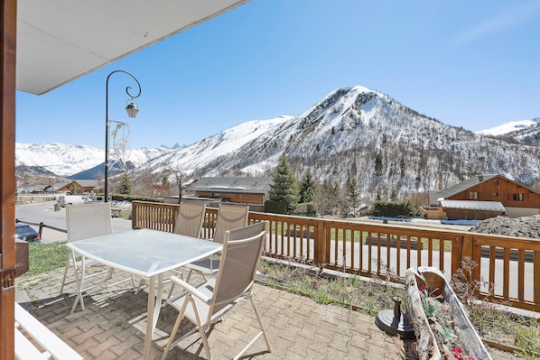 A patio with a table and chairs, a wooden fence, and a mountain view.