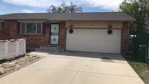 A residential house with a garage, brick facade, and a white picket fence.
