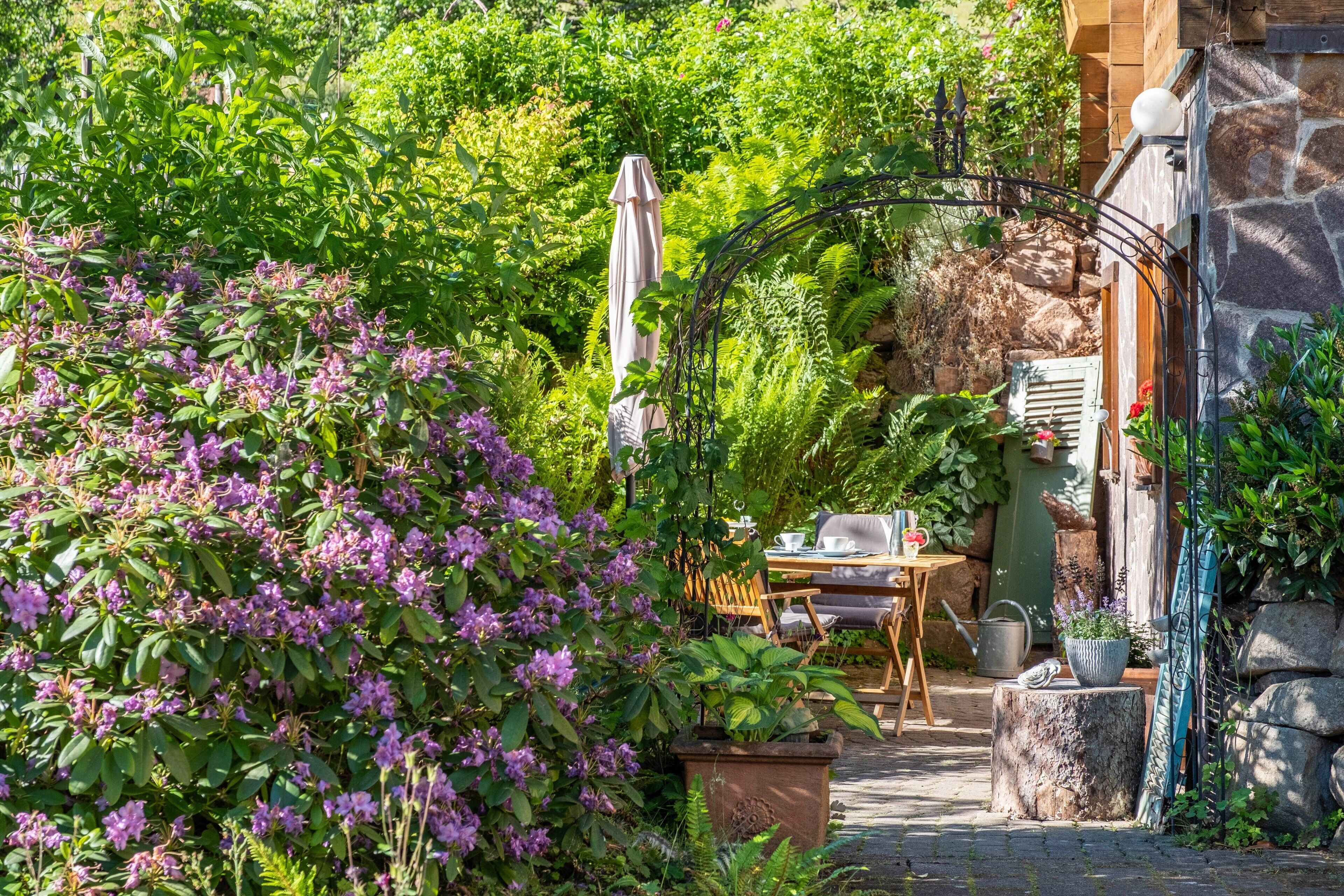 Un jardin avec une table et des chaises, un mur en pierre et une clôture en bois.
