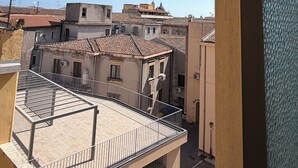 Une vue depuis un balcon donnant sur une zone urbaine densément peuplée, avec des bâtiments traditionnels et un ciel bleu dégagé.