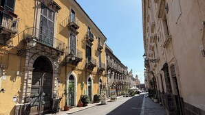 Une rue bordée de bâtiments historiques, avec un pavé et un ciel dégagé.