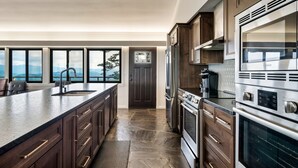A modern kitchen with a large island, stainless steel appliances, and a view of the mountains through large windows.