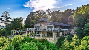 A stone house with a balcony, surrounded by dense greenery.