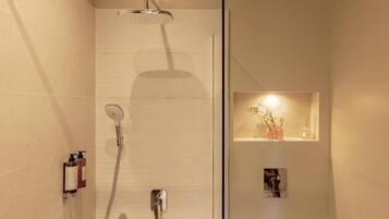 Ein modernes Badezimmer mit Dusche, Handtuchhalter und einer kleinen Ablage mit Dekoration.