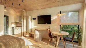 Un espacio habitable moderno y abierto con cocina, comedor y un amplio ventanal con vistas a zonas verdes.