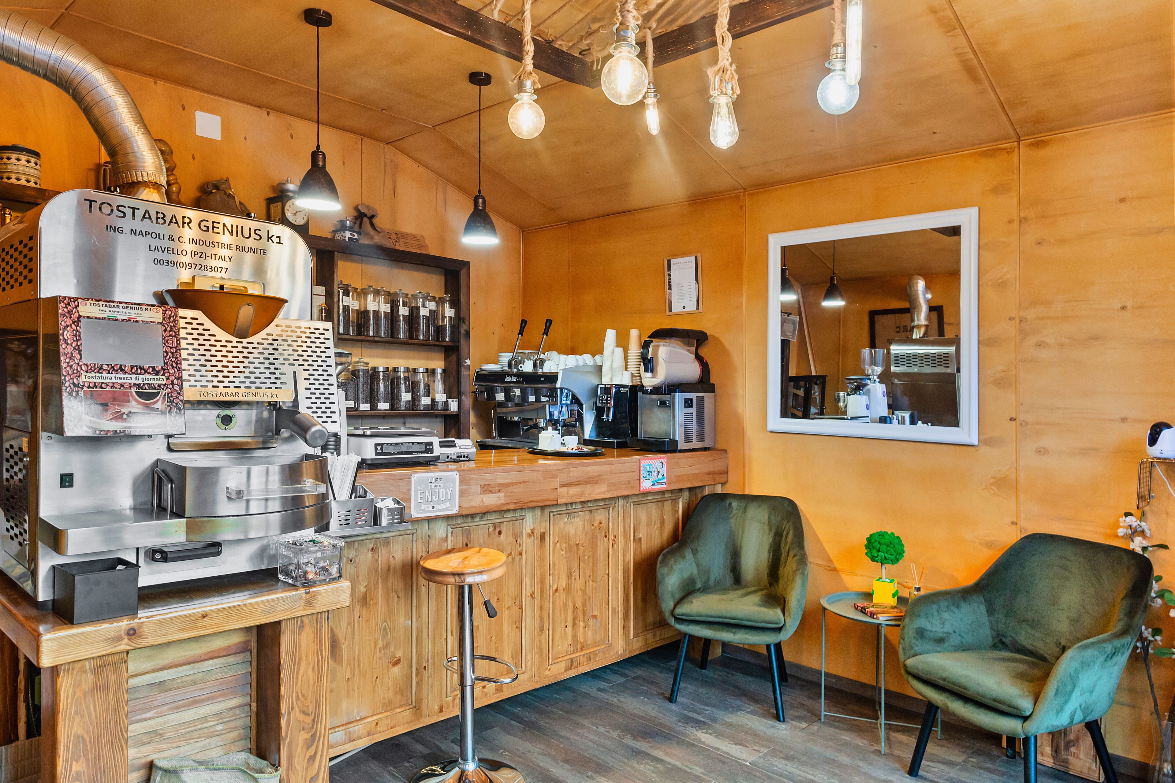 Angolo bar con macchina del caffè, posti a sedere e arredamento in legno.