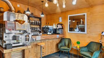 Angolo bar con macchina del caffè, posti a sedere e arredamento in legno.
