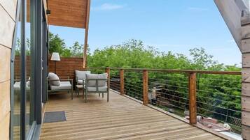 Una terraza de madera con mobiliario exterior y vistas a zonas verdes.