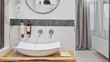 Un baño moderno con tocador de madera, espejo redondo y lavamanos grande.