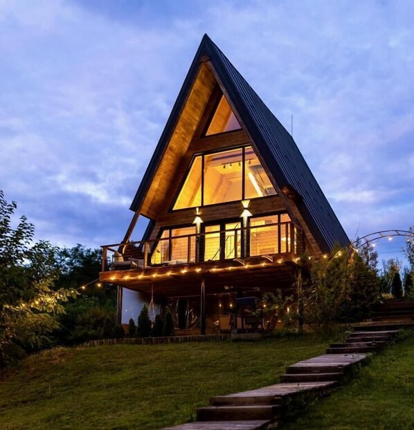 A modern, triangular-shaped building with large windows and a wooden deck. - Arta Chalet - Nature Retreat (Fantanele)