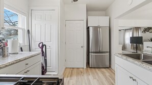 Una cocina moderna con armarios blancos, un refrigerador de acero inoxidable y piso de madera.