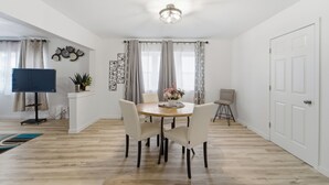 Un comedor con una mesa redonda de madera, cuatro sillas y una lámpara colgante.