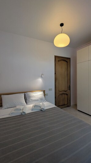 A bedroom with a bed, a wooden door, and a wardrobe.