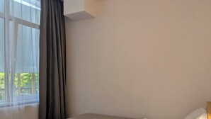 A bedroom with a bed, a window with curtains, and a ceiling light. - The Leafy Terrace Flat (Kobuleti)