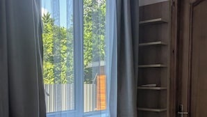A room with a built-in bench under a window, a wooden door, and a view of greenery outside. - The Leafy Terrace Flat (Kobuleti)