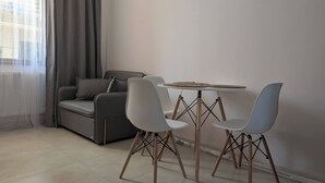 A modern living room with a grey sofa, two white chairs, and a small round table. - The Leafy Terrace Flat (Kobuleti)