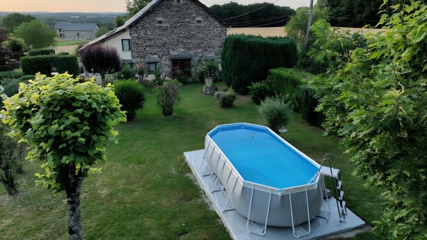 Ein Steinhaus mit einem Swimmingpool in einem Garten.