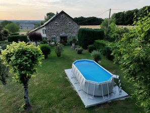 Una casa de piedra con piscina en un jardín.