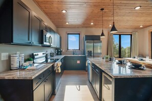 A modern kitchen with dark cabinetry, stainless steel appliances, and a large island with seating. - 5BR Luxury Cabin・Pool・Near Dollywood / Water Parks (Sevierville)